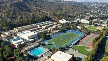 an aerial view of a campus with a soccer field and a pool